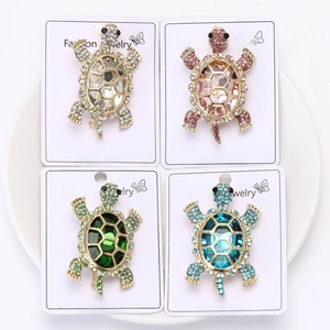 Detail of four crystal turtle brooches in clear, pink, green, and blue rhinestone colors