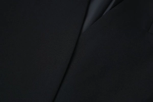 Detail of high-quality black worsted fabric texture on elegant V-neck puff sleeve blazer