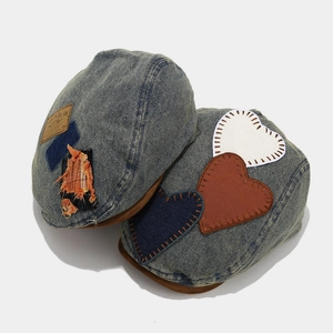 Detail of denim berets featuring heart-shaped patches and vintage leather label accents