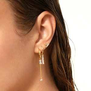 Detail shot of gold tassel chain earrings with rectangle zircons on a model's ear