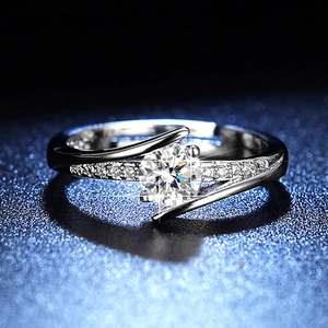 Macro shot of silver ring with round moissanite and twisted band on blue background