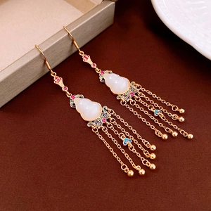 Detailed macro view of gold-plated gourd earrings with colorful stones and tassels