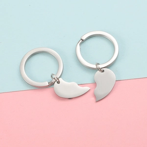 Polished silver heart split keychain set for couples on pink and blue background