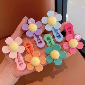 Hand holding colorful floral hair clips for kids in various sweet candy colors