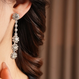 Detailed close-up of sparkling silver floral tassel earrings worn by a model