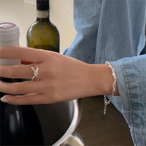 Close-up of 925 sterling silver knotted ring and bracelet set worn with denim shirt