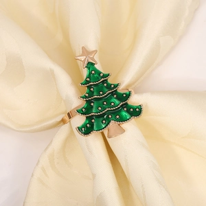 Detail of green enamel Christmas tree napkin ring with gold star on a beige fabric