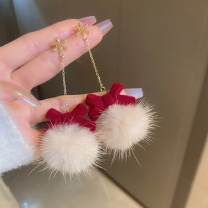 Detail of winter snowflake earrings featuring red velvet bows and soft white pom-poms
