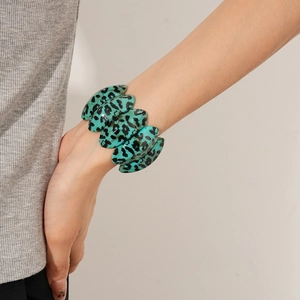 Macro detail of oval teal leopard print resin links on a stylish stretch bracelet