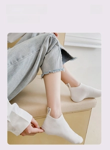 Close-up of white invisible socks featuring an embroidered heel label with lo.PSA text