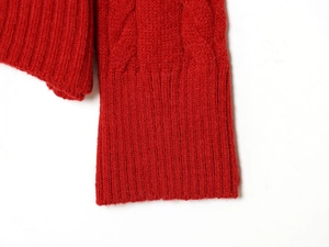 Détail de la manche d'un pull en maille torsadée avec poignets côtelés rouge foncé