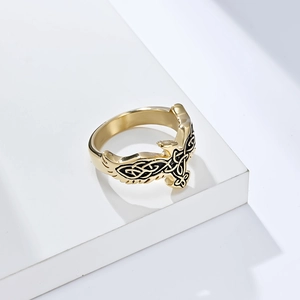 Detail of gold Nordic Celtic eagle ring with intricate black carvings on a stone step