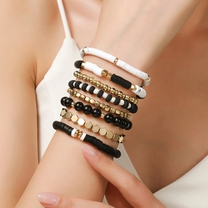 Detail of 8-piece black and white Heishi bead bracelet set with golden accents on wrist
