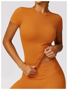 Detail of high-elastic orange compression sports T-shirt and yoga leggings set