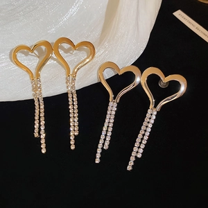 Golden heart tassel earrings with sparkling crystals on elegant white silk fabric