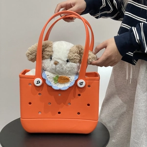 Detail of bright orange EVA beach bag with holes and cute stuffed puppy accessory