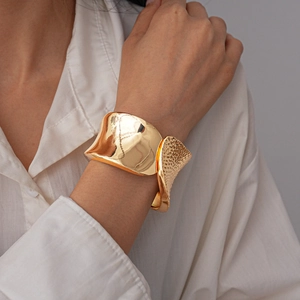 Macro shot of wide gold bangle featuring dual-texture hammered and polished finishes