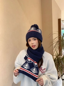 Dettaglio del set cappello e sciarpa in maglia con motivi di fiocchi di neve e pini