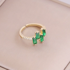 Detailed close-up of 18K gold ring with green rectangular zircons and micro-pave crystals