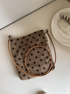 Detailed macro view of vintage brown polka dot corduroy crossbody bag on a white table