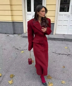 Outdoor shot of a woman in a stylish red long coat with a lapel collar and waist-cinching fit