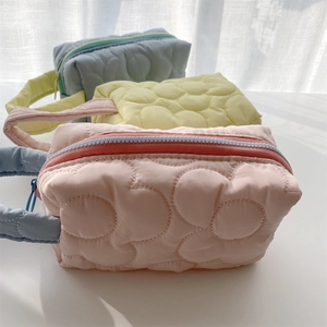 Detailed view of floral quilted makeup bags in pink, yellow and blue-grey with zipper
