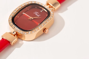 Close-up of red oval dial ladies watch with sparkling rhinestones and gold bezel
