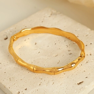 Minimalist gold-plated bamboo texture stainless steel bangle on a stone base