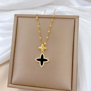 Macro shot of gold star and black clover necklace with cubic zirconia on jewelry stand