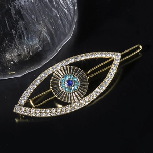 Close-up of golden eye-shaped hair clip with sparkling blue and clear rhinestones