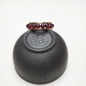 Detailed macro view of handmade wire-wrapped ring with red garnet beads and gold wire