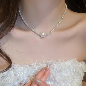 Detail of silver woven chain necklace with a single round white pearl on collarbone