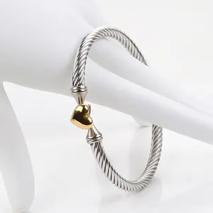 Silver-tone twisted cable bangle with a polished gold-plated heart charm for women