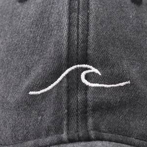 Macro detail of wave pattern embroidery on a washed dark gray cotton baseball cap