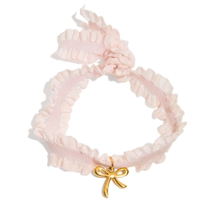 Pink lace choker with a golden bow pendant in a minimalist flat lay composition