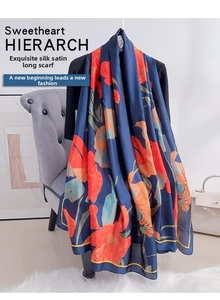 Detail of elegant floral satin scarf in navy blue and orange draped over a black outfit