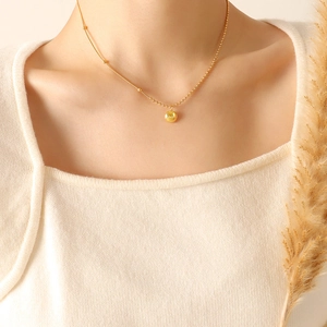 Collier minimaliste à perle dorée avec chaîne mixte porté par un mannequin femme