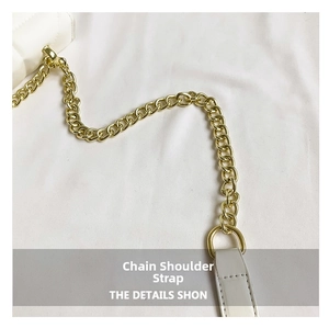 Detail of light gold chain strap connected to white quilted leather on the small square bag