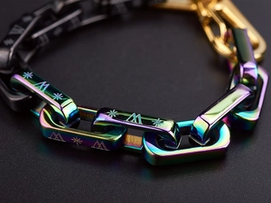 Macro detail of multicolored titanium steel chain with engraved star and letter patterns