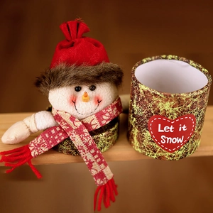 Detail of a snowman plush gift box with Let it Snow text on a wooden shelf display