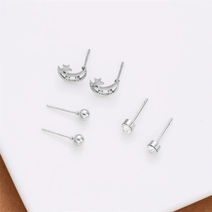 Detailed view of silver heart and star stud earring set on a white minimalist platform