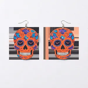 Detail view of orange acrylic skull earrings with colorful floral embossed patterns