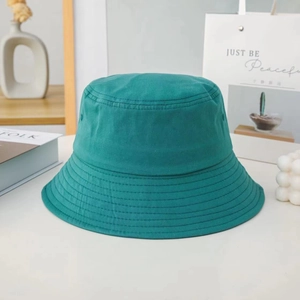 Teal cotton bucket hat displayed on white table with aesthetic lifestyle props