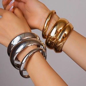 Close-up of minimalist layered chunky metal bangles in polished gold and silver finish