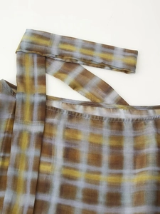 Detailed view of sheer brown plaid chiffon fabric with asymmetric neck strap detail