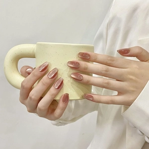 Dettaglio di unghie finte fatte a mano nude cat eye pomelo con finitura lucida elegante