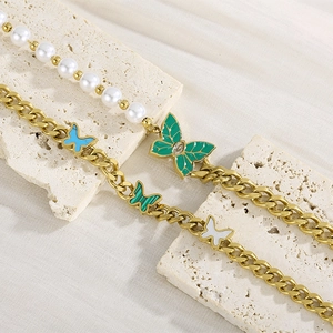 Vintage gold butterfly bracelet with pearls and green enamel on a stone texture background