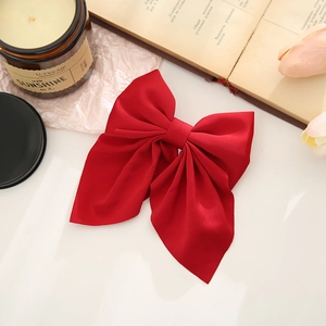 Detailed view of a dark red fabric bow hair clip on a vintage background with books