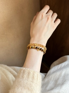 Close-up of double-layer tiger eye and citrine beaded bracelets with a gold coin charm