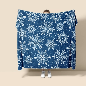 Close-up of soft navy blue flannel blanket featuring white Christmas snowflake patterns